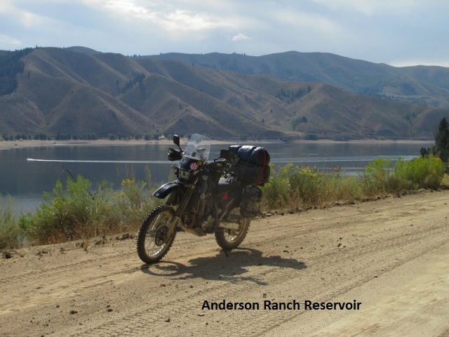 A person riding a motorcycle on a dirt road next to a lake

Description automatically generated with medium confidence